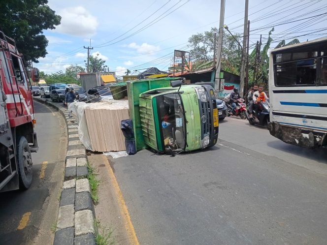 
					Muatan Bergeser, Truk Triplek Pengangkut Terguling di Tikungan Jalan Raya Kemang-Parung